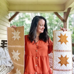 Puede incluir: Dos caminos de mesa acolchados hechos a mano con un dise&ntilde;o de estrella. Un camino de mesa es beige con estrellas blancas y el otro es blanco con estrellas doradas.