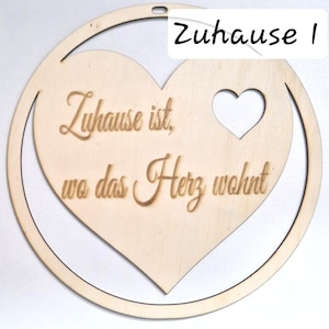 Könnte beinhalten: Ein herzförmiges Wandbild aus Holz mit einem Herz-Ausschnitt und einem kreisförmigen Rahmen. Der Text "Zuhause ist, wo das Herz wohnt" ist auf dem Herzen eingraviert. Der Text "Zuhause 1" befindet sich oben.