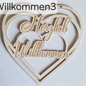 Könnte beinhalten: Eine herzförmige Holzdekoration mit den Worten "Herzlich Willkommen" in einer kursiven Schriftart ausgeschnitten. Das Design zeigt drei ineinander verschachtelte Herzformen mit dem Text in der Mitte. Das Wort "Willkommen3" befindet sich in der oberen linken Ecke.