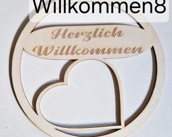 May include: A wooden welcome sign with the words "Willkommen8" and "Herzlich Willkommen" engraved. The sign has a circular shape with a heart-shaped cutout in the center. The sign is made of light-colored wood.
