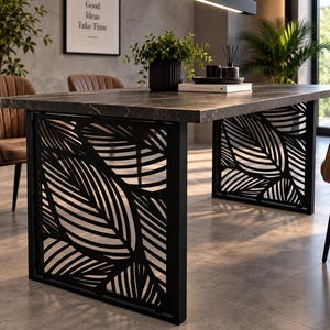May include: A rectangular dining table with a dark grey marble-patterned top and two black metal base supports featuring a laser-cut leaf pattern. The table is accompanied by brown upholstered chairs with vertical channel tufting.