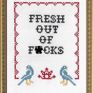 May include: A white cross-stitch embroidery with a red border. The embroidery says "FRESH OUT OF F*CKS" in black thread. Two blue birds with yellow beaks and feet are on either side of a red flower.