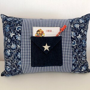 Pode incluir: Travesseiro xadrez azul e branco com um bolso de ganga e uma estrela branca. O bolso contém um cartão que diz "Desejo..." e um lápis vermelho.