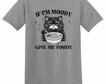 May include: A gray t-shirt featuring a black and white illustration of a grumpy cat holding chopsticks over a bowl of food. The text "IF I'M MOODY GIVE ME FOODY" is printed above and below the cat image.