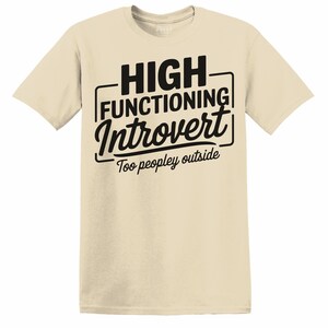 Könnte beinhalten: Sandfarbenes T-Shirt mit dem schwarzen Text "HIGH FUNCTIONING Introvert Too peopley outside". Der Text ist mittig auf der Vorderseite platziert. Das Shirt hat kurze Ärmel und einen Rundhalsausschnitt.