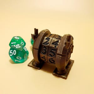 Può includere: Un lanciatore di dadi di colore marrone stampato in 3D con i numeri da 1 a 6 su ogni lato. Il lanciatore è su un tavolo con tre dadi verdi.