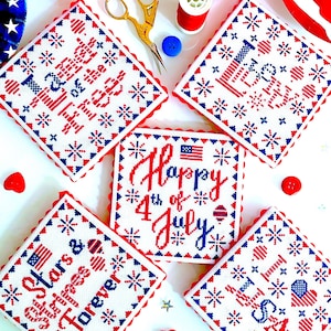 Könnte beinhalten: Fünf weiße quadratische Kreuzstich-Stickereien mit rotem, weißem und blauem Garn. Die Designs beinhalten "Stars & Stripes Forever", "Happy 4th of July", "I Love USA", "Land of the Free" und "Home of the Brave".