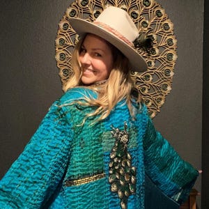 May include: A handmade wooden sign with the text "Welcome" in a playful font. The sign is painted white with a distressed finish, and features a decorative floral design in shades of pink and green. It measures approximately 12 inches wide.