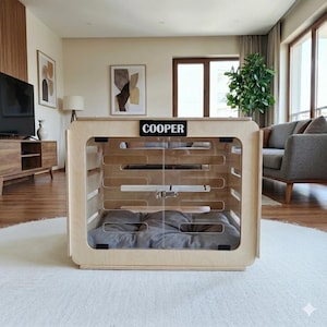 Modern indoor wooden dog house made from birch plywood with ventilation slats and an open acrylic door, shown with a soft gray dog cushion inside.