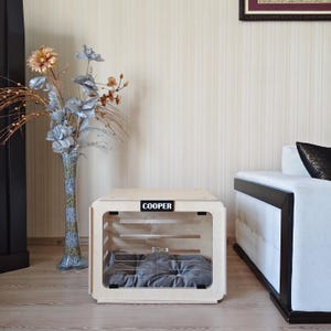 Interior of the indoor wooden dog house showing a spacious sleeping area with a removable gray dog bed cushion.