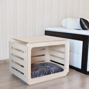 Front view of a birch plywood indoor dog crate furniture featuring an open acrylic door and ventilated wooden panels.