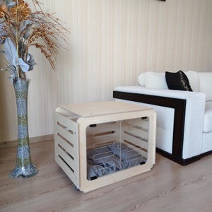 Indoor wooden dog house designed to fit small, medium, and large dogs, shown in a home environment for size reference.