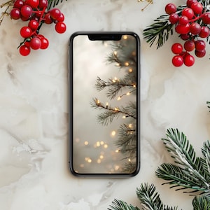 May include: A smartphone displays a Christmas tree with string lights. Red berries and green pine branches with white accents surround the phone on a marble surface. The phone has a black bezel.