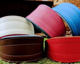 May include: Four leather dog collars in different colors: brown, gray, red, and pink. Each collar has a contrasting colored trim and stitching.