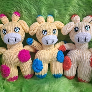 May include: Three knitted giraffe toys with colorful accents. The giraffes are yellow with pink, blue, and orange accents.
