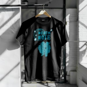 Könnte beinhalten: Schwarzes T-Shirt mit einer blauen Grafik eines Charakters aus dem Anime Death Note. Die Grafik enthält den Text "Death Note" und Sterne.