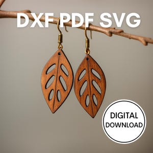 May include: A pair of wooden leaf-shaped earrings with cut-out details, hanging from gold-colored hooks. The earrings are a warm brown color and are suspended from a natural branch. The image includes the text "DXF PDF SVG" and "DIGITAL DOWNLOAD".