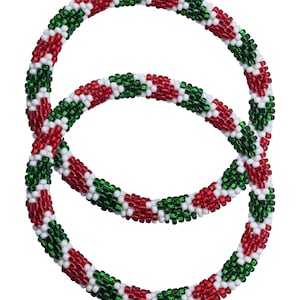 Puede incluir: Dos pulseras de cuentas circulares. Las pulseras presentan un patrón de cuentas rojas, verdes y blancas. El diseño recuerda a las decoraciones festivas, con las cuentas muy juntas.