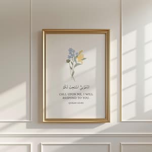 May include: A framed wall art print featuring a small bouquet of blue and yellow flowers above Arabic calligraphy and the English text: CALL UPON ME, I WILL RESPOND TO YOU. QURAN 40:60. The artwork is enclosed in a thin, metallic gold frame.
