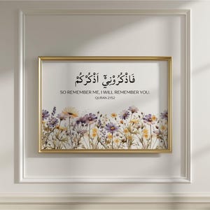 May include: A rectangular wall art print in a thin gold frame featuring a field of watercolor-style wildflowers in shades of yellow, purple, and white. The text reads: FADHKURUNI ADHKURKUM, SO REMEMBER ME, I WILL REMEMBER YOU. QURAN 2:152.