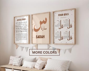 May include: Three framed wall art prints with light wood frames. The left print features Ayatul Kursi text, the centre print displays the Arabic letter seen and the name Sarah, and the right print shows the Four Quls text. A banner hangs below.