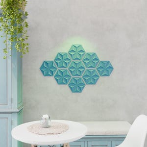 Op de afbeelding: Een geometrisch wandkunstwerk in tealblauw gemaakt van 3D hexagonale tegels. De tegels zijn in een symmetrisch patroon gerangschikt, wat een modern en abstract ontwerp creëert.