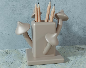 May include: A beige mushroom-shaped pencil holder with five pencils inside. The holder has a square base and three mushroom-shaped arms.