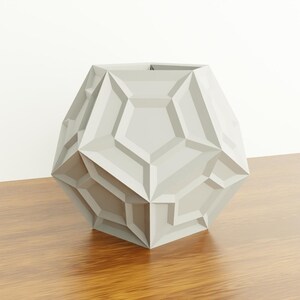 May include: A geometric, light gray vase with a faceted design. The vase is made of a smooth, hard material and has a unique, modern look.