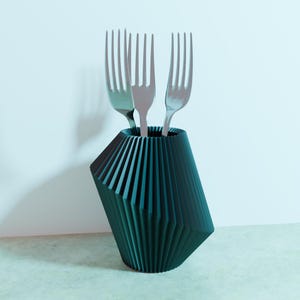 May include: A teal blue, geometric, pleated ceramic utensil holder with three silver forks inside.