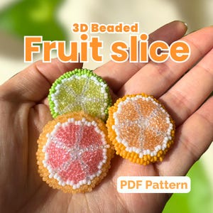 Puede incluir: Tres adornos de rodajas de fruta con cuentas: una lima, un pomelo y una naranja. La lima es verde y blanca, el pomelo es rosa y blanco, y la naranja es naranja y blanca. También se ve el texto "3D Beaded Fruit Slice" y "PDF Pattern".