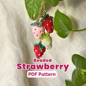 Peut inclure: Un motif PDF de fraises perlées. L'image montre quatre fraises perlées rouges, roses et blanches, avec des feuilles perlées vertes. Les fraises sont suspendues à une chaîne dorée. Le texte "Beaded Strawberry PDF Pattern" est affiché.