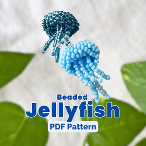 Peut inclure: Deux méduses perlées dans des tons de bleu. Les méduses ont des corps arrondis et des tentacules pendants. Le texte "Beaded Jellyfish PDF Pattern" est affiché en bleu et blanc.