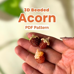 Pode incluir: Três pequenas bolotas 3D feitas de pequenas contas de vidro. As bolotas apresentam corpos castanhos com chapéus bege ou dourados. O texto sobreposto diz 3D Beaded Acorn PDF Pattern. As contas formam um padrão estruturado e repetitivo.