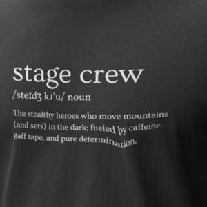 May include: Black t-shirt with the words "stage crew" in white, along with a definition. The definition describes the stage crew as stealthy heroes who move mountains, fueled by caffeine, gaff tape, and pure determination.