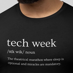 Könnte beinhalten: Schwarzes T-Shirt mit dem weißen Schriftzug "tech week" und einer Definition. Die Definition lautet: "Der theatralische Marathon, bei dem Schlaf optional und Wunder obligatorisch sind."