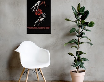 May include: Black poster featuring a stylized illustration of two hands, one reaching down to the other, holding a red flower. The text "TO THE WORLD WE DREAM ABOUT, AND THE ONE WE LIVE IN NOW" is printed in red at the bottom.