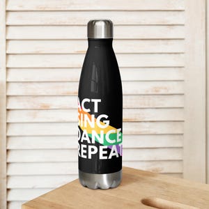 May include: A black stainless steel water bottle with a rainbow design and the text "Act Sing Dance Repeat".