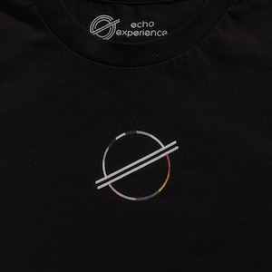Könnte beinhalten: Ein schwarzes T-Shirt mit einem kreisförmigen Logo, das einen mehrfarbigen Verlauf am Rand und zwei parallele diagonale Linien durch die Mitte aufweist. Das innere Nackenetikett zeigt den Text echo experience mit einem kreisförmigen Grafiklogo.
