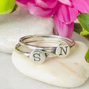 May include: Two silver rings with engraved letters, one ring has the letter "S" and the other ring has the letter "N".