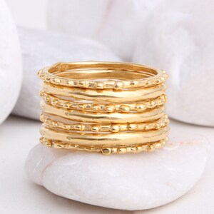 May include: A set of eight gold stacking rings with a textured beaded design.