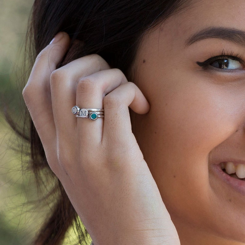 May include: A silver ring with a turquoise stone and a silver ring with the letter "M" engraved on it.