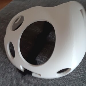 以下が含まれることがあります： 鼻と口の大きな開口部と複数の穴のある白いプラスチック製のフェイスマスクです。