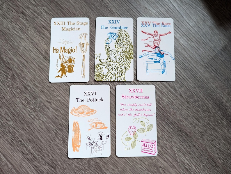 Może przedstawiać: Pięć kart z ilustracjami i tekstem. Karty są białe z czarnymi obramowaniami. Tekst na kartach jest czarny i brązowy. Ilustracje są czarne, brązowe, niebieskie i zielone. Karty są ponumerowane XXIII, XXIV, XXV, XXVI i XXVII. Tekst na kartach brzmi: XXIII Magik sceniczny, To magia!, XXIV Hazardzista, XXV Wyścig, XXVI Potluck, XXVII Truskawki, "Po prostu nie można powiedzieć, gdzie truskawki i galaretka się zaczynają!"