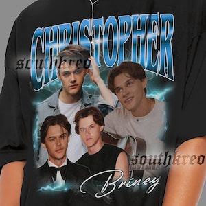 Peut inclure: T-shirt noir avec un motif graphique. Le motif comprend le mot "CHRISTOPHER" en bleu et blanc, ainsi que des images de quatre hommes. Le mot "Briney" est &eacute;crit en cursive en dessous.
