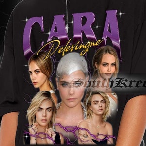 May include: Black oversized t-shirt featuring a graphic of Cara Delevingne with the text "Cara Delevingne" in purple and gold. The design includes multiple images of the model. The background is a black and white lightning pattern.