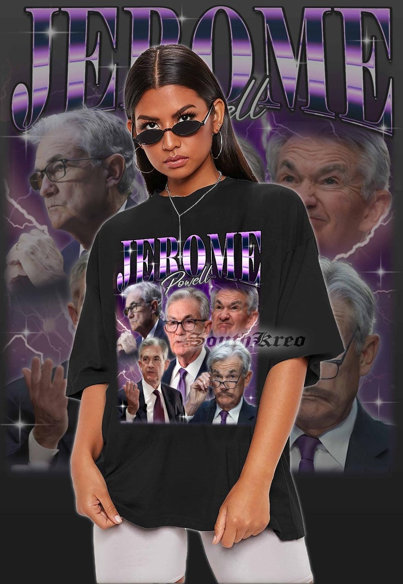 May include: A black t-shirt with a graphic print of Jerome Powell, the chairman of the Federal Reserve, in a collage of images. The text "Jerome Powell" is printed in purple and white letters on the shirt. The shirt is being worn by a person with long black hair and sunglasses.