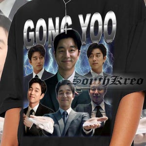 May include: Black t-shirt with a graphic print of five men. The text "GONG YOO" is printed in silver letters across the top of the shirt. The men are all wearing suits and are posed in a variety of ways. The background is a black and white lightning bolt pattern.