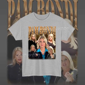 May include: A grey t-shirt with a graphic print of Pam Bondi, a former Florida Attorney General. The graphic features a collage of images of Bondi, including a close-up of her face and a photo of her with other people. The text "PAM BONDI" is printed in gold letters on the shirt.