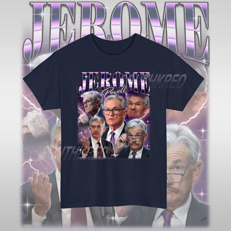 May include: A navy blue t-shirt with a graphic print of Jerome Powell, the current chairman of the Federal Reserve, in a retro style. The text "Jerome Powell" is printed in purple on the shirt.