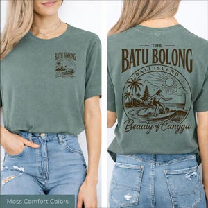 May include: Moss green t-shirt with a front and back graphic. The front graphic says "Batu Bolong Beauty of Canggu" with a small illustration. The back graphic says "The Batu Bolong Bali Island Beauty of Canggu" with a surfer illustration.